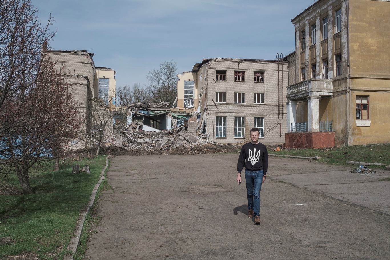 Алексей Гончаренко идет на фоне разрушенной школы. Краматорск, Украина. 10 апреля 2022 года. Фото: Marko Djurica / Reuters / Scanpix / LETA