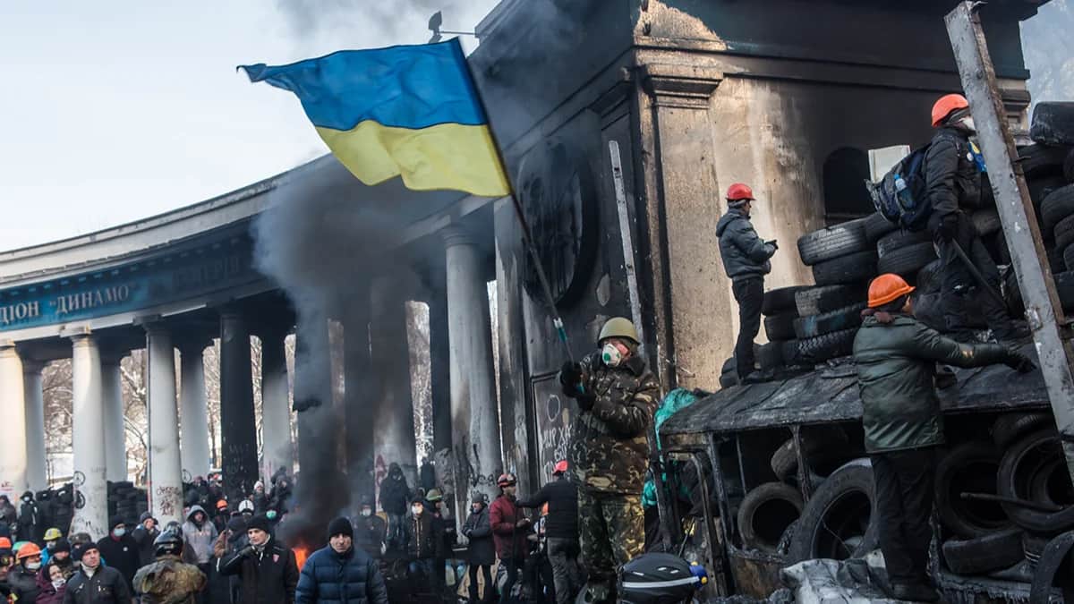 Участник антиправительственной демонстрации размахивает украинским флагом во время столкновений с милицией на улице Грушевского возле стадиона «Динамо» 25 января 2014 г. в Киеве. Фото: Brendan Hoffman / Getty Images