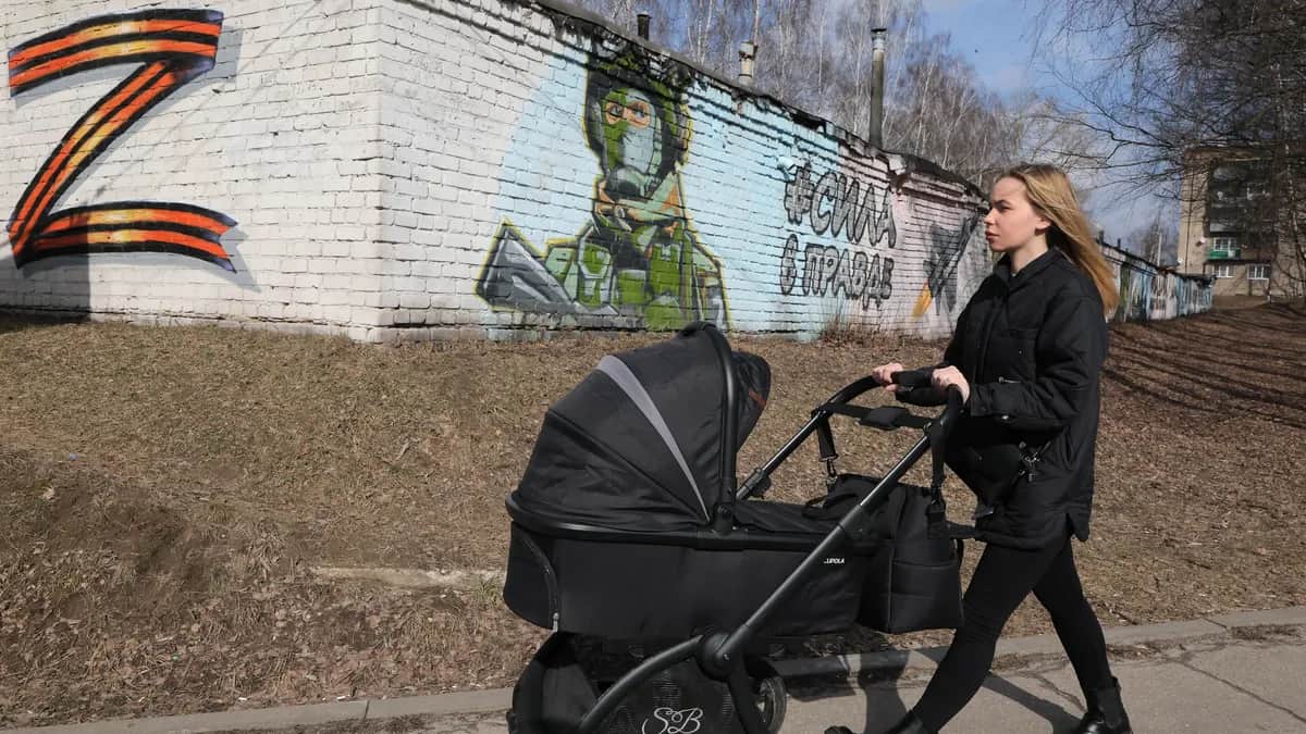 A woman pushes her baby past pro-Kremlin street art in the Moscow region town of Pavlovsky Posad, Russia, 14 March 2025. Photo: EPA / MAXIM SHIPENKOV
