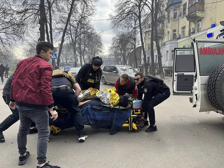 Люди помогают раненому на месте ракетного удара в центре города Сумы, Украина, 13 апреля 2025 года. Фото: Telegram-канал премьер-министра Украины Дениса Шмыгаля / EPA-EFE