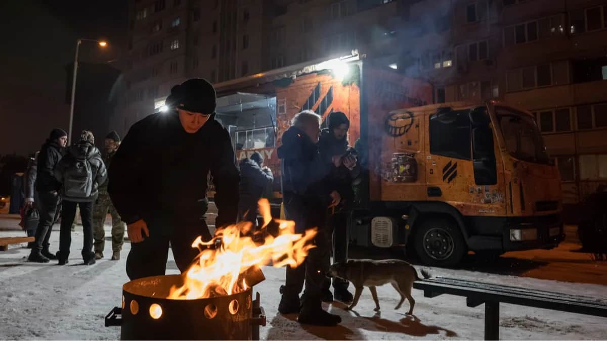 Жители Киева греются у огня возле мобильной кухни, организованной ветеранами 3-ей отдельной штурмовой бригады, Украина, 28 января 2026 года. Фото: Maxym Marusenko / EPA