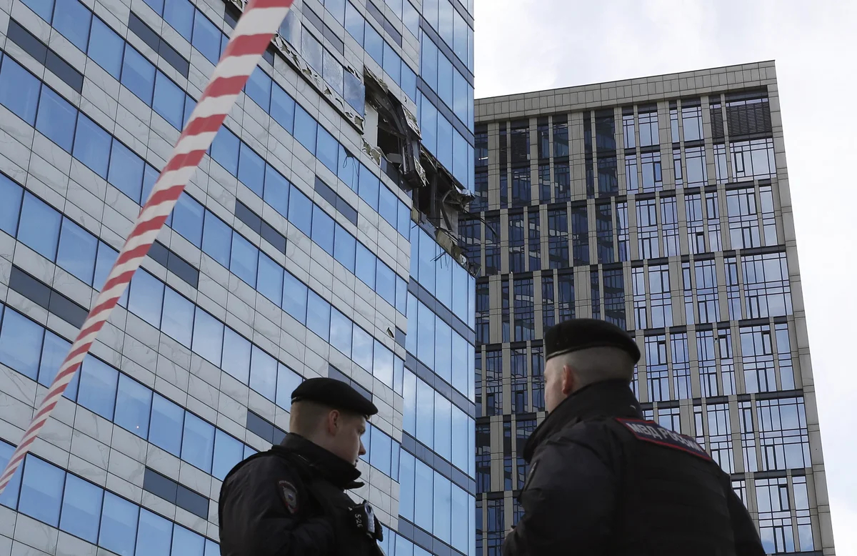 Полицейские стоят перед повреждённым зданием после атаки дронов в Москве, 30 июля 2023 года. Фото: Юрий Кочетков / EPA