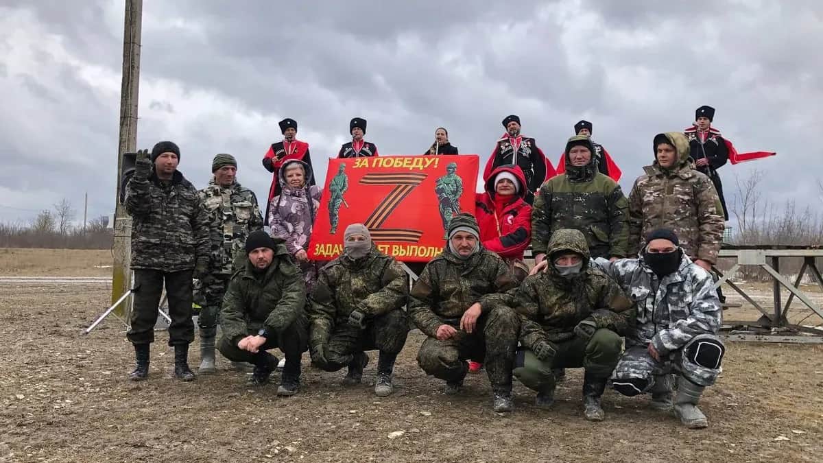 Anna Gromyko poses with Russian soldiers in an official Red Cross jacket and holding a banner saying "For victory. The mission will be completed." Photo: Anna Gromyko / Telegram&nbsp;