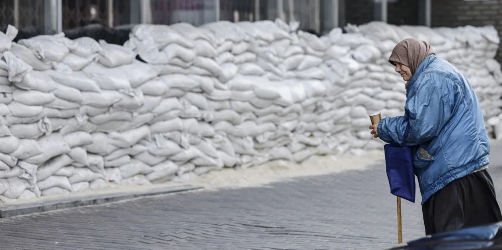 A woman begs for money in front of a barricade of sandbags in Dnipro, Ukraine, 27 October 2022. Photo: EPA-EFE/HANNIBAL HANSCHKE